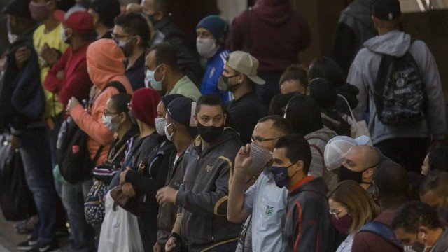 Em São Paulo, pessoas usam máscaras enquanto aguardam por chegada do trem para ir ao trabalho